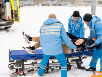 Brigade of paramedics in winter uniform putting unconscious man on stretcher